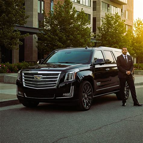 Black Cadillac Escalade with chauffeur outside an upscale property