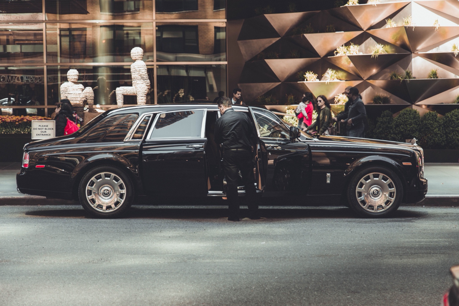 Luxury chauffeur opening the door of a black vehicle in Toronto at night