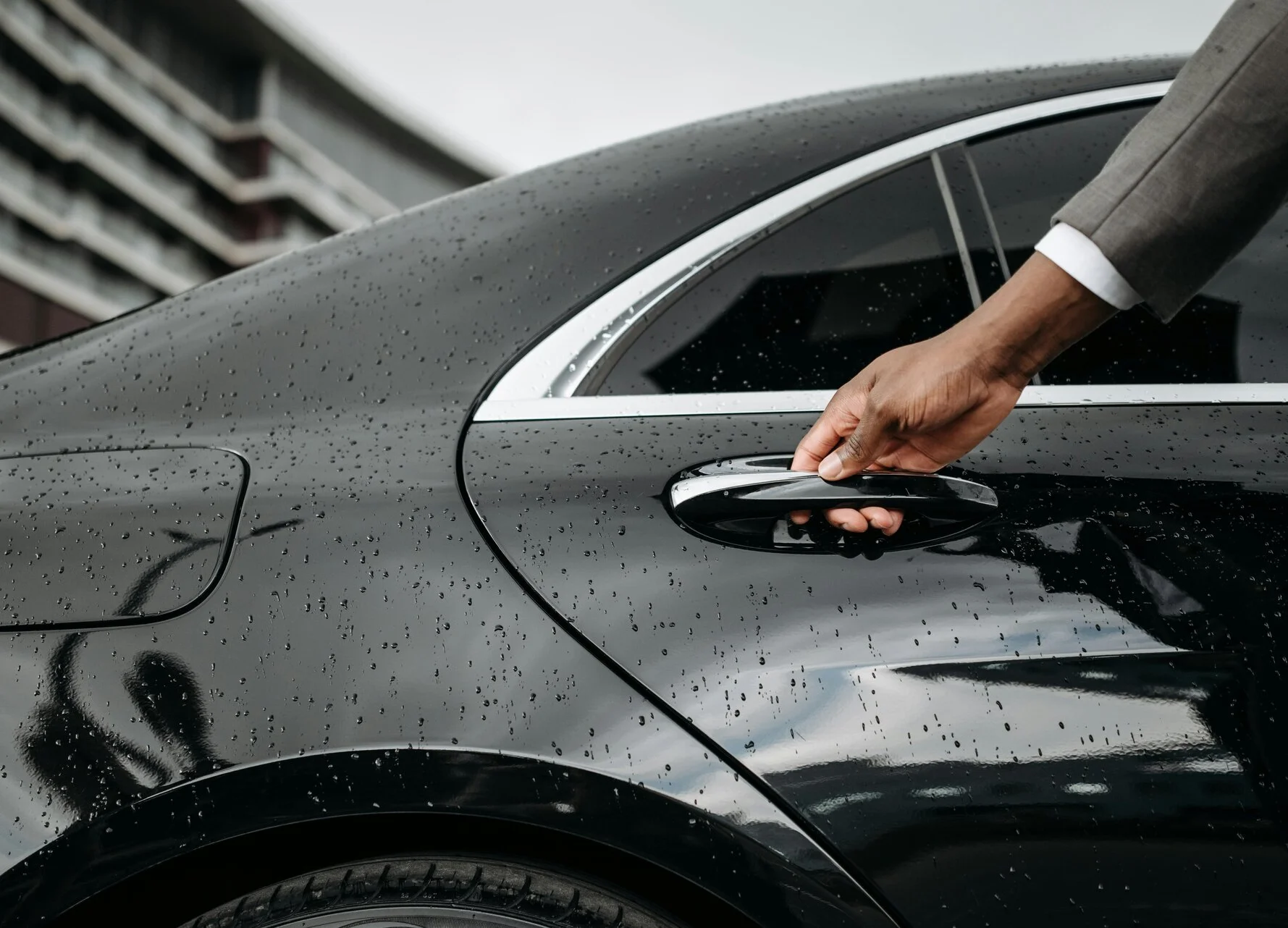 Chauffeur hand opening a premium vehicle door